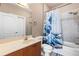 Well-lit bathroom features a tub, shower with a blue wave curtain, and a vanity with generous counter space at 6319 Sunset Bay Cir, Apollo Beach, FL 33572
