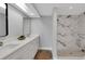 Bright bathroom featuring double sinks, a modern vanity, and a walk-in shower with stylish marble-look tile at 6914 Harbor Dr, Hudson, FL 34667