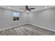 Bright bedroom with wood-look flooring, a large window, and a ceiling fan for added comfort and style at 6914 Harbor Dr, Hudson, FL 34667