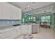 Bright kitchen with white cabinets, granite countertops, and view of the living and dining areas at 724 Chipper Dr, Sun City Center, FL 33573