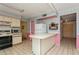 View of the kitchen offering white appliances, tiled floors, and an island counter, with adjacent doorway leading to foyer at 7317 W Pocahontas Ave, Tampa, FL 33634