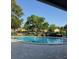 Community pool with brick trim, seating, mature trees and landscaping surrounded by decorative, black, metal fencing at 7605 W Deleon Ct, Tampa, FL 33615