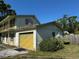 Brick garage attached to the two-story home, with a yellow garage door and some bushes at 8244 125Th St, Seminole, FL 33772