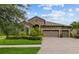 Charming home featuring a three-car garage, manicured lawn, and stone facade, and a brick-paved driveway at 1002 Cavour Ct, Brandon, FL 33511