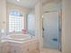 Bright bathroom with tub, large window and tiled shower at 11137 Woodland Waters Blvd, Weeki Wachee, FL 34613