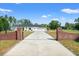 Long concrete driveway flanked by brick columns leads to a home with ample parking space at 11137 Woodland Waters Blvd, Weeki Wachee, FL 34613