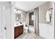 Well-lit bathroom with tile flooring, a wood vanity, a shower/tub combo, and updated fixtures at 112 W Mohawk Ave, Tampa, FL 33604