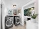 A well-lit laundry room featuring a modern washer and dryer with storage shelves at 112 W Mohawk Ave, Tampa, FL 33604