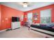 Cozy bedroom with an orange accent wall, a comfortable bed, and a dresser with a TV, perfect for relaxation at 11550 Lake Lucaya Dr, Riverview, FL 33579