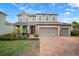 Charming two-story home with a three-car garage and a brick-paved driveway and landscaped front yard at 11550 Lake Lucaya Dr, Riverview, FL 33579