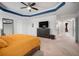Bright main bedroom with tray ceilings, large dresser with TV and hallway access at 11550 Lake Lucaya Dr, Riverview, FL 33579