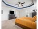 Spacious main bedroom with tray ceilings, ceiling fan and dresser with a wall mounted TV at 11550 Lake Lucaya Dr, Riverview, FL 33579
