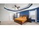 Inviting primary bedroom with a tray ceiling, ceiling fan, and stylish decor at 11550 Lake Lucaya Dr, Riverview, FL 33579