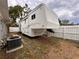 Spacious white and gold RV with exterior storage is parked on a grassy lot behind a white wood fence at 1233 Belleair Rd, Clearwater, FL 33756