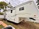 Spacious white and gold RV with exterior storage and a pull-out awning is parked on a grassy lot at 1233 Belleair Rd, Clearwater, FL 33756