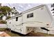 Spacious white and gold RV with exterior storage and a pull-out awning is parked on a grassy lot at 1233 Belleair Rd, Clearwater, FL 33756