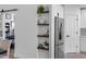 Hallway with decorative shelves adjacent to kitchen and stainless steel refrigerator at 13409 Fawn Springs Dr, Tampa, FL 33626