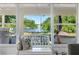 Relaxing sun room featuring a white bench, screened windows, and serene lake views at 13409 Fawn Springs Dr, Tampa, FL 33626