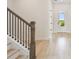 Bright hallway with wood-look flooring, staircase with dark metal railings, and white trim at 1586 Running Tide Pl, Sarasota, FL 34240