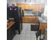 Functional kitchen with wooden cabinets, black appliances, and white tile flooring at 1663 Cambridge Dr, Clearwater, FL 33756
