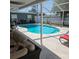 A relaxing outdoor pool with outdoor furniture underneath a screened-in patio at 1663 Cambridge Dr, Clearwater, FL 33756