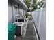 A narrow side yard with white gravel, AC units, a white fence, and a concrete walkway at 1663 Cambridge Dr, Clearwater, FL 33756