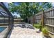 Backyard patio with a fire pit and privacy fence with mature landscaping at 1666 Pine Pl, Clearwater, FL 33755