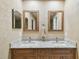 Bathroom vanity featuring dual sinks, granite countertop and modern fixtures, illuminated by recessed lighting and sconces at 1666 Pine Pl, Clearwater, FL 33755