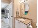 Granite vanity in a bright bathroom with a round mirror, featuring an exit door to the backyard at 1666 Pine Pl, Clearwater, FL 33755