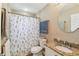 Neutral-toned bathroom featuring a floral shower curtain, matching round mirror, and granite countertop at 1666 Pine Pl, Clearwater, FL 33755