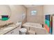 Well-lit bathroom with a tiled tub, granite countertop, and round mirror at 1666 Pine Pl, Clearwater, FL 33755