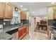 Well-lit kitchen featuring stainless appliances, granite countertops, wood cabinets and a view of the dining room at 1666 Pine Pl, Clearwater, FL 33755