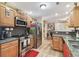 Stylish kitchen featuring wood cabinets, stainless steel appliances, granite countertops, and view of the living area at 1666 Pine Pl, Clearwater, FL 33755