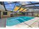 An in-ground screened pool with shade sails is nestled within a secure fenced-in yard at 1666 Pine Pl, Clearwater, FL 33755
