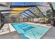 An outdoor in-ground pool is enclosed by screen with shade sails and surrounding greenery at 1666 Pine Pl, Clearwater, FL 33755