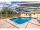 Backyard view of pool with yellow house, brick patio, screened enclosure, and a wood fence at 1713 W Louisiana Ave, Tampa, FL 33603