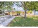 Charming yellow home featuring a welcoming front yard, palm trees, and covered carport at 1713 W Louisiana Ave, Tampa, FL 33603