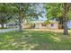 Quaint yellow home with mature trees, manicured lawn, and charming front entrance at 1713 W Louisiana Ave, Tampa, FL 33603