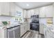 Modern kitchen featuring white cabinets, stainless steel appliances, and granite countertops at 1713 W Louisiana Ave, Tampa, FL 33603