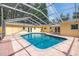 Backyard pool with yellow house, brick patio, screened enclosure, landscaping, and a wood fence at 1713 W Louisiana Ave, Tampa, FL 33603