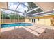 Backyard pool with screened enclosure, brick patio, and yellow house in a sunny outdoor setting at 1713 W Louisiana Ave, Tampa, FL 33603