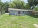 Home's backyard featuring a small deck, lush green lawn, and a mix of greenery at 17236 Spring Valley Rd, Dade City, FL 33523