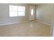 Bright living room with large window, white door, neutral walls, and neutral tiled flooring at 17236 Spring Valley Rd, Dade City, FL 33523