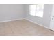 Bright, neutral living room with large window, white door, neutral walls, and neutral tiled flooring at 17236 Spring Valley Rd, Dade City, FL 33523