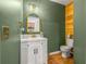 Stylish half bath with green walls, wood accents, and modern vanity with gold fixtures at 1749 Sedgefield Ct, Odessa, FL 33556