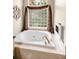 Inviting bathtub with gold fixtures and elegant window that brings natural light into the space at 1802 Oak Ridge Rd, Safety Harbor, FL 34695