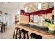 Kitchen bar counter with granite countertop and three black bar stools, a view to the game room at 1802 Oak Ridge Rd, Safety Harbor, FL 34695