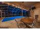 Covered patio features an outdoor dining table and chairs overlooking a sparkling swimming pool at night at 1802 Oak Ridge Rd, Safety Harbor, FL 34695