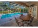 Covered patio features an outdoor dining table and chairs overlooking a sparkling swimming pool at 1802 Oak Ridge Rd, Safety Harbor, FL 34695