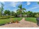 Backyard view of a home with mature palm tree, lush lawn, and brick pathway to the waterway at 18816 Tracer Dr, Lutz, FL 33549